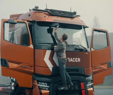 Model year 2025 : Renault Trucks T High Smart Racer : lifestyle (Renault Trucks Hero Zip Hoodie) driver on windshield access steps cleaning rearview mirror)